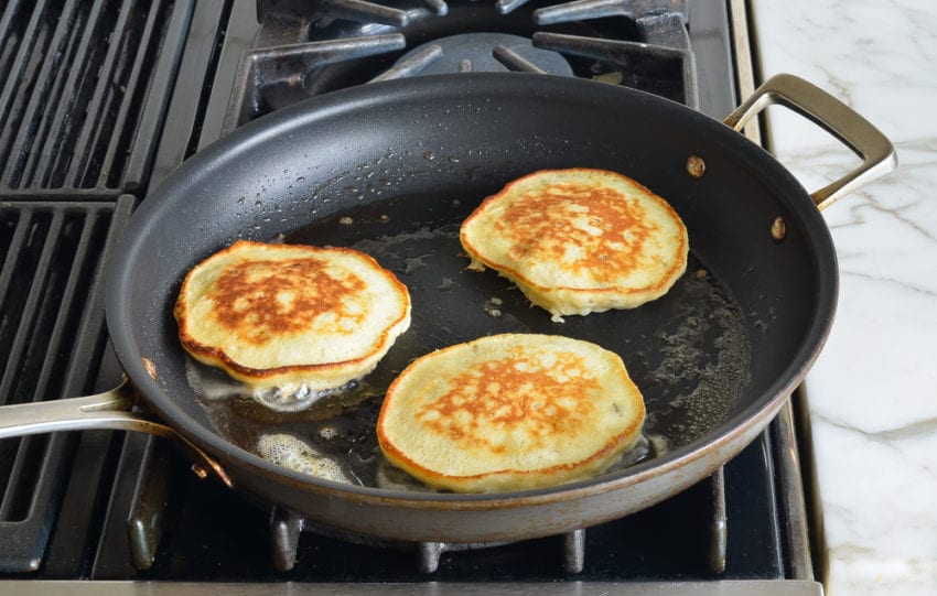 Banana pancakes cooking on a skillet.