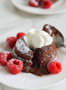 Molten chocolate cake on a plate with raspberries.