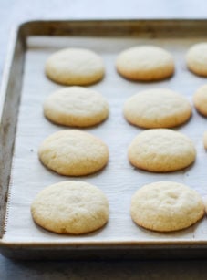 Sugar cookies on a lined baking sheet.