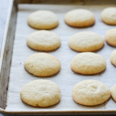 Sugar cookies on a lined baking sheet.