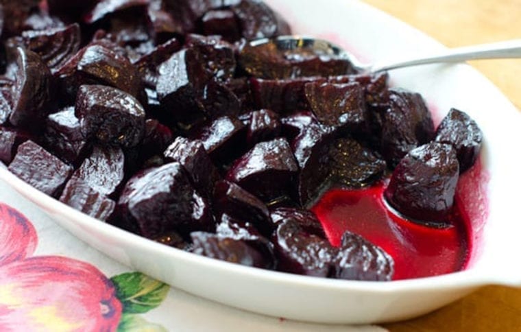 Spoon in a dish of roasted beets.