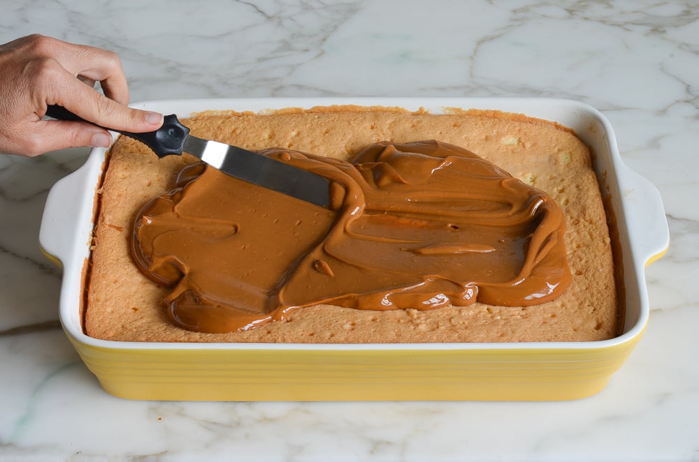 spreading dulce de leche glaze on cake