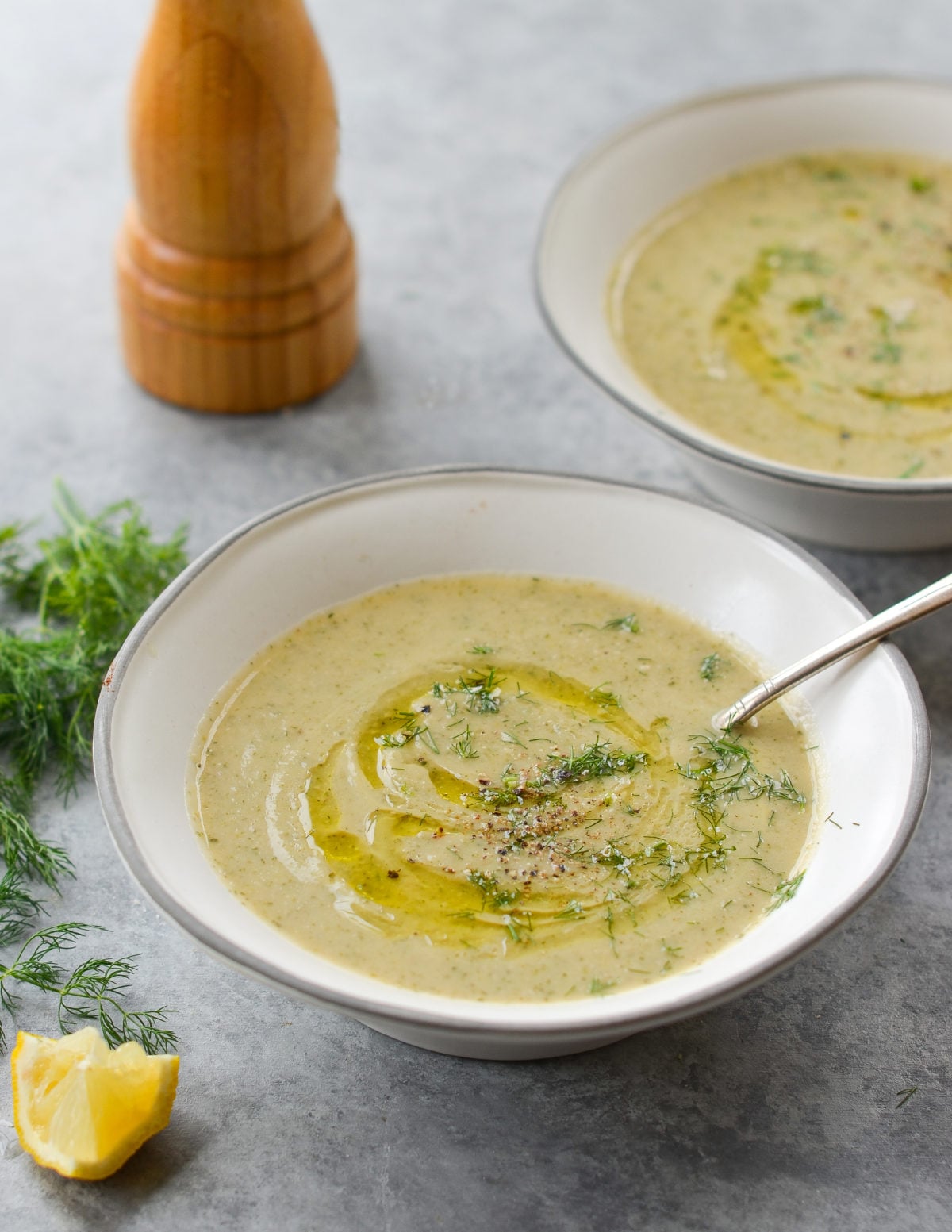 Spoon in a bowl of creamy zucchini soup with walnuts and dill.