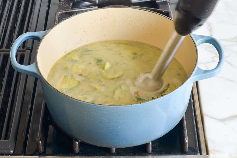 pureeing the zucchini soup with a stick blender 