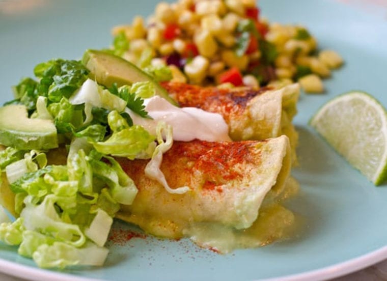 Plate with chicken enchiladas with tomatillo sauce.