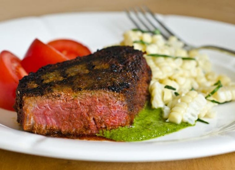 Grilled, spice-rubbed beef tenderloin with chimichurri on a plate.