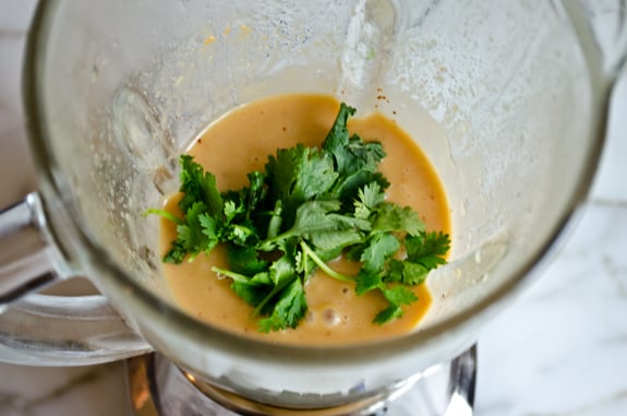 Cilantro in a blender with dressing ingredients.