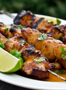 Honey, lime, and sriracha chicken skewers on a plate.
