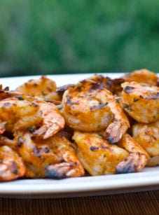 Grilled shrimp skewers with tomato, garlic, and herbs on a plate.