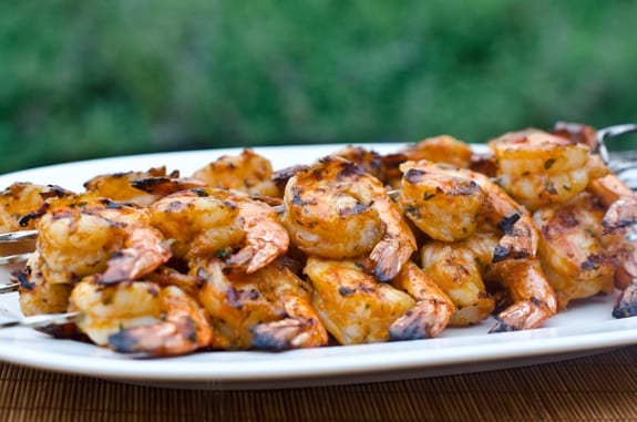 Grilled shrimp skewers with tomato, garlic, and herbs on a plate.