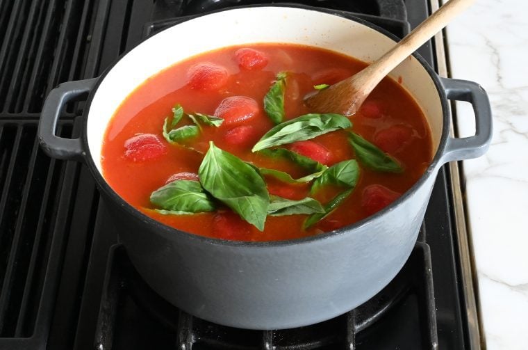 Adding the tomatoes, water, orange juice, sugar and salt to the pot