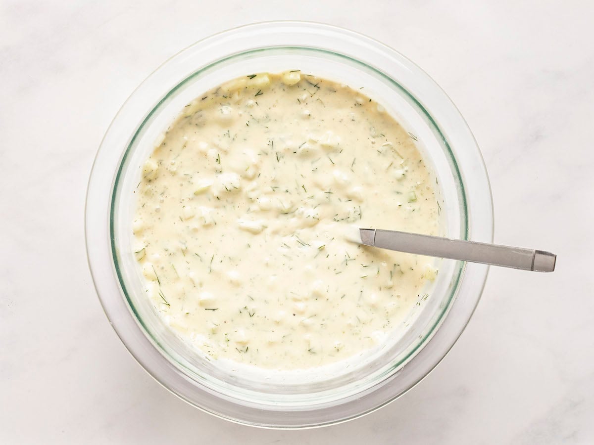 mixed cucumber yogurt sauce in glass mixing bowl.