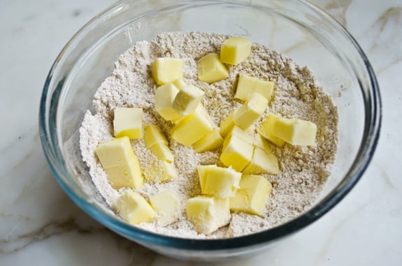 Pieces of butter in a bowl of dry ingredients.