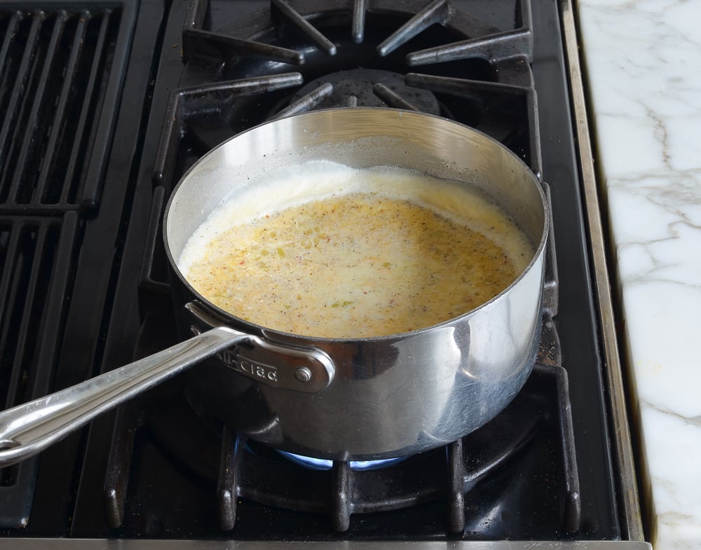 Milk mixture boiling in a sauce pan.
