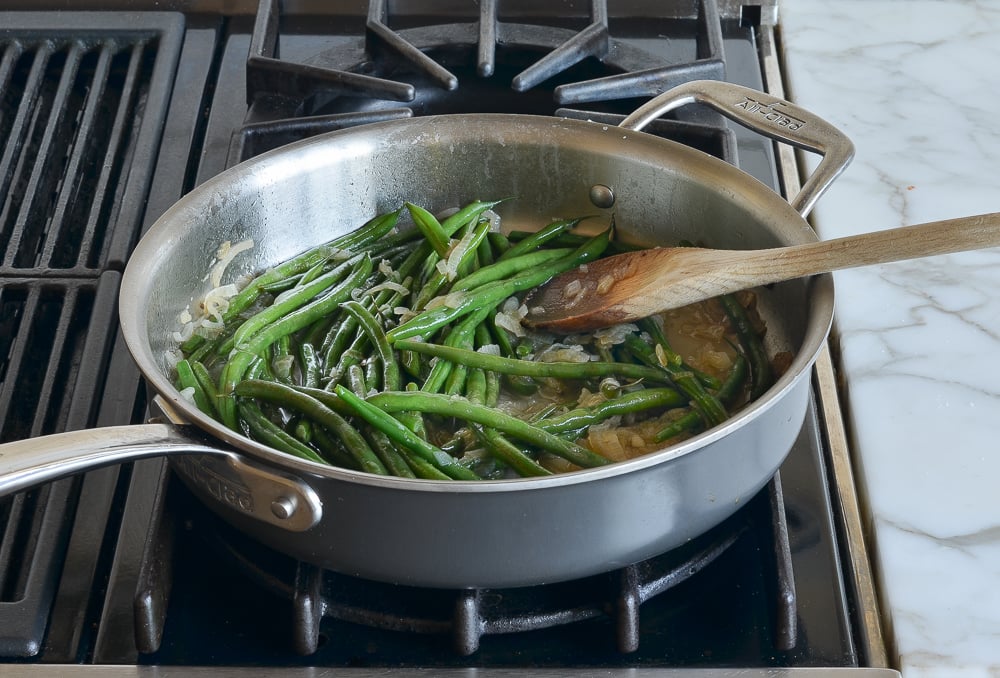 Simmered beans in a skillet with shallots.