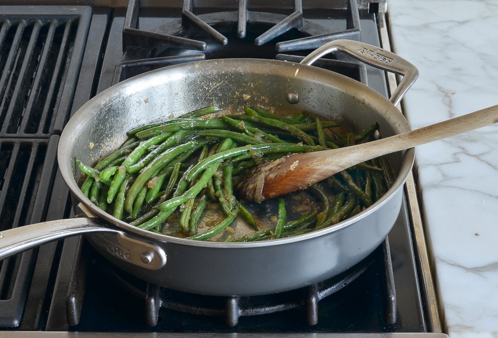 Simmered beans in a skillet with shallots.