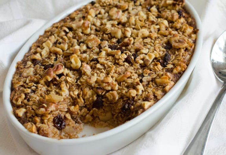 Baked oatmeal with apples and raisins in a white dish.