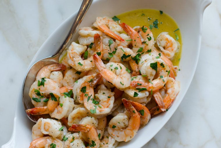 Spoon in a dish of garlic butter shrimp.