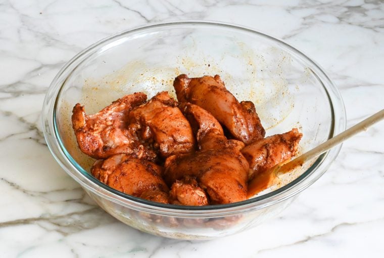 tossing the chicken thighs with the spice rub