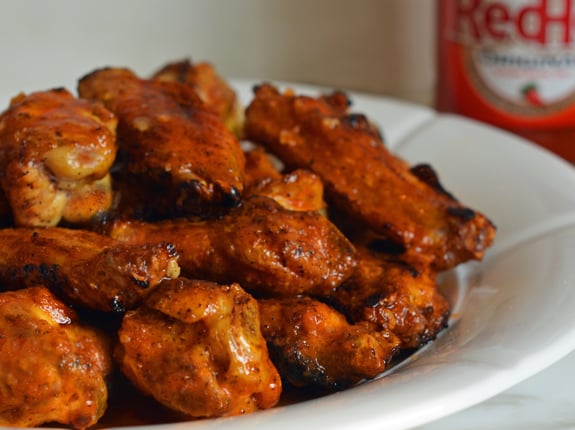 Plate of grilled chicken wings with seasoned buffalo sauce.
