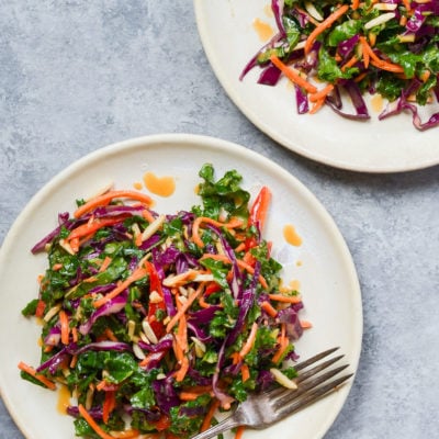 Kale salad with ginger peanut dressing on plates.