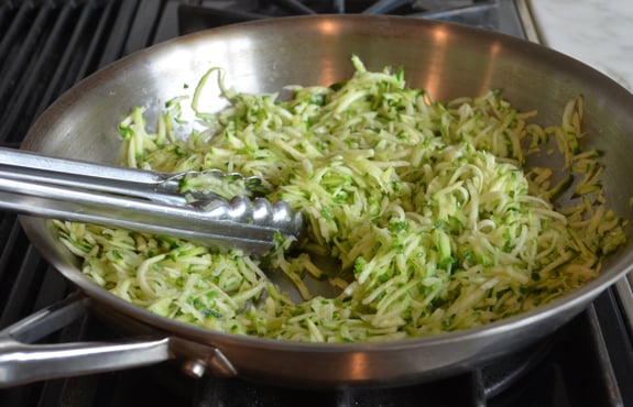 Shredded zucchini and garlic in a skillet.
