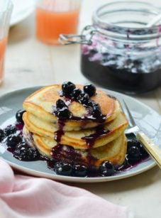 Stack of blueberry pancakes drizzled with blueberry-maple syrup.