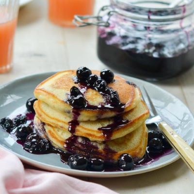 Stack of blueberry pancakes drizzled with blueberry-maple syrup.