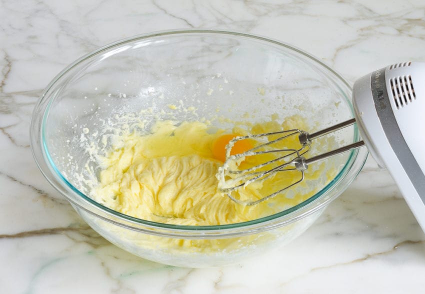 Egg in a bowl with creamed butter and sugar.