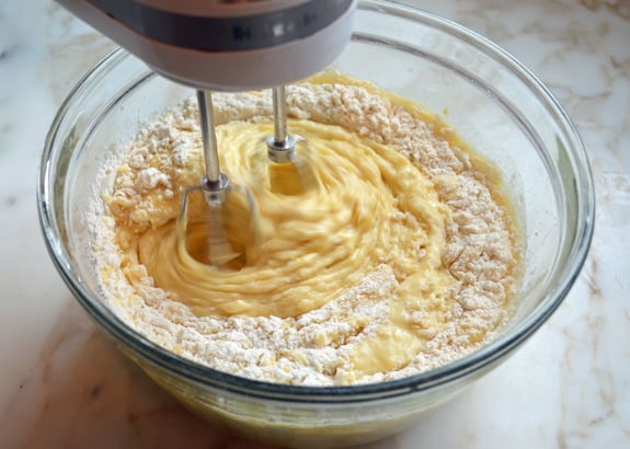 Electric mixer beating dry ingredients into wet ingredients.