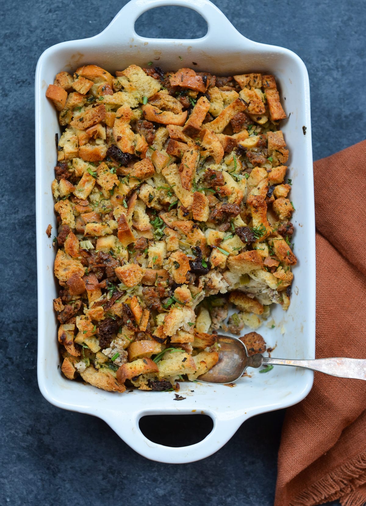 Spoon in a baking dish of sausage and herb stuffing.