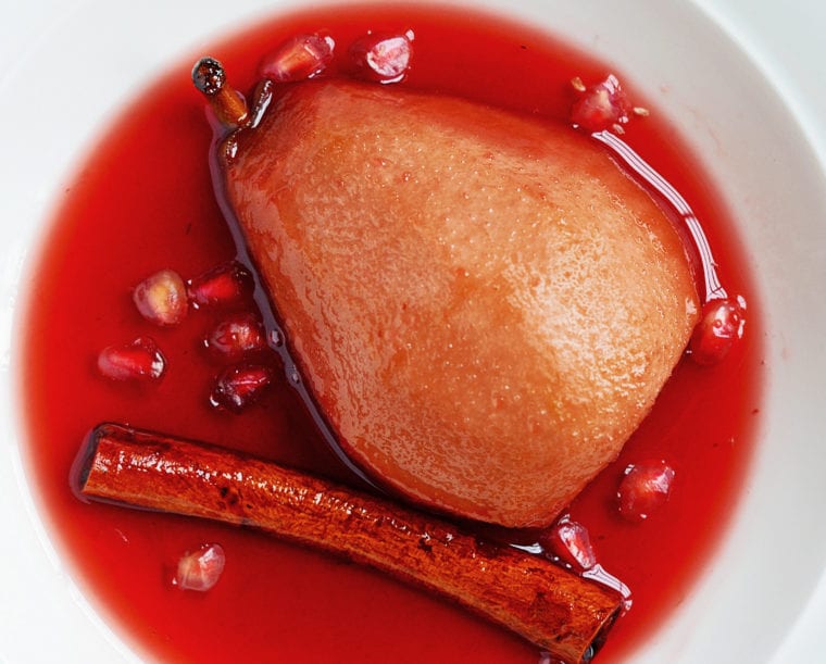 Plate with a baked pear in spiced pomegranate syrup.