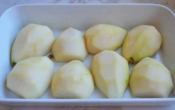 Halved, peeled pears in a baking dish.
