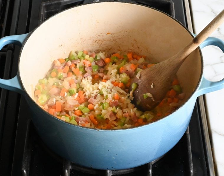 adding the garlic to the cooked vegetables.
