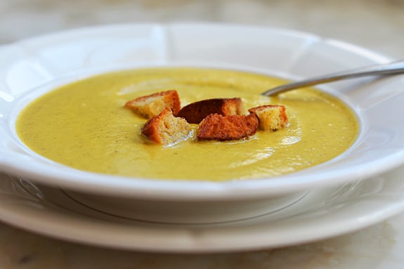 Spoon in a bowl of broccoli and gruyere soup with homemade croutons.