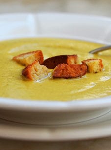Bowl of broccoli soup topped with croutons.