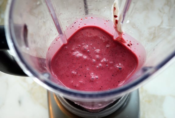 Berry, banana, and pomegranate smoothie in a blender.