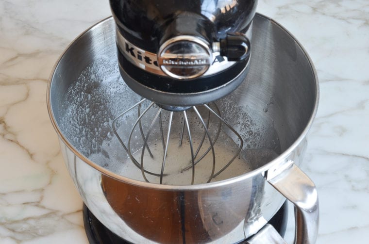 Egg white mixture in the bowl of a stand mixer.