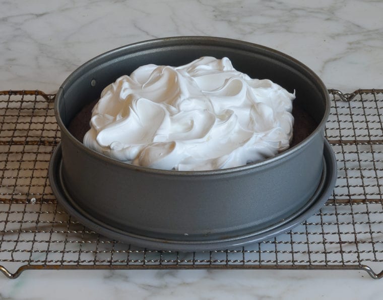 swirling meringue over baked cake 