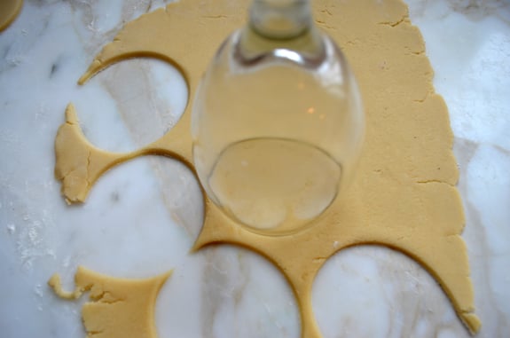 Wine glass cutting circles from rolled dough.