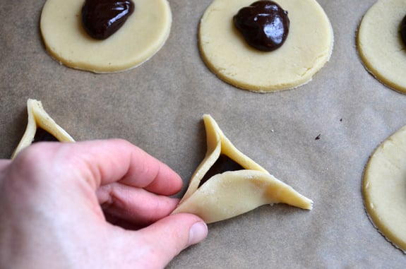 Person pinching dough into a triangle around chocolate.