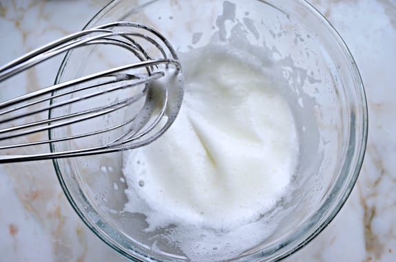 Bowl of whisked egg whites with soft peaks.