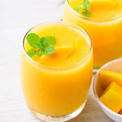 tropical peach mango smoothies in glasses garnished with fresh mint