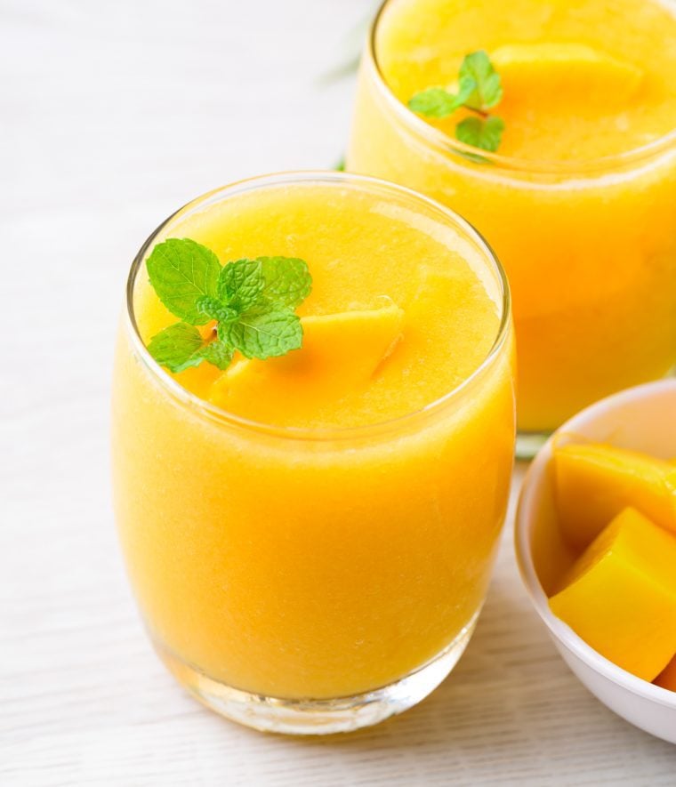 tropical peach mango smoothies in glasses garnished with fresh mint