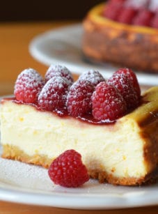 Slice of ricotta cheesecake with fresh raspberries on a plate.