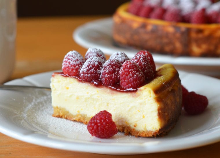Slice of ricotta cheesecake with fresh raspberries on a plate.