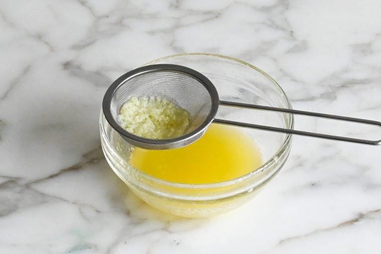 Sieve straining garlic.