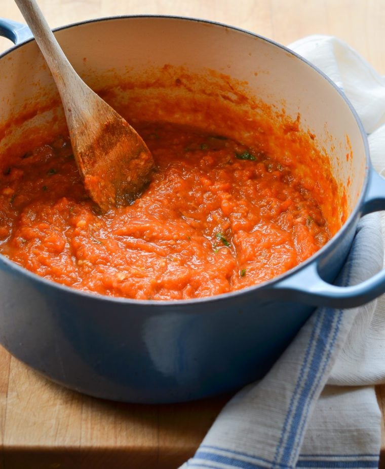 Wooden spoon in a Dutch oven of homemade tomato sauce.