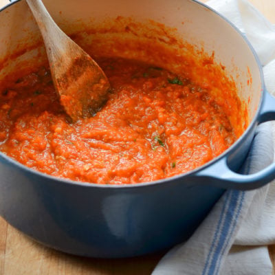 Wooden spoon in a Dutch oven of homemade tomato sauce.