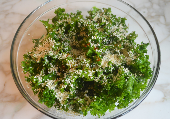 Sesame seeds over kale in a bowl.